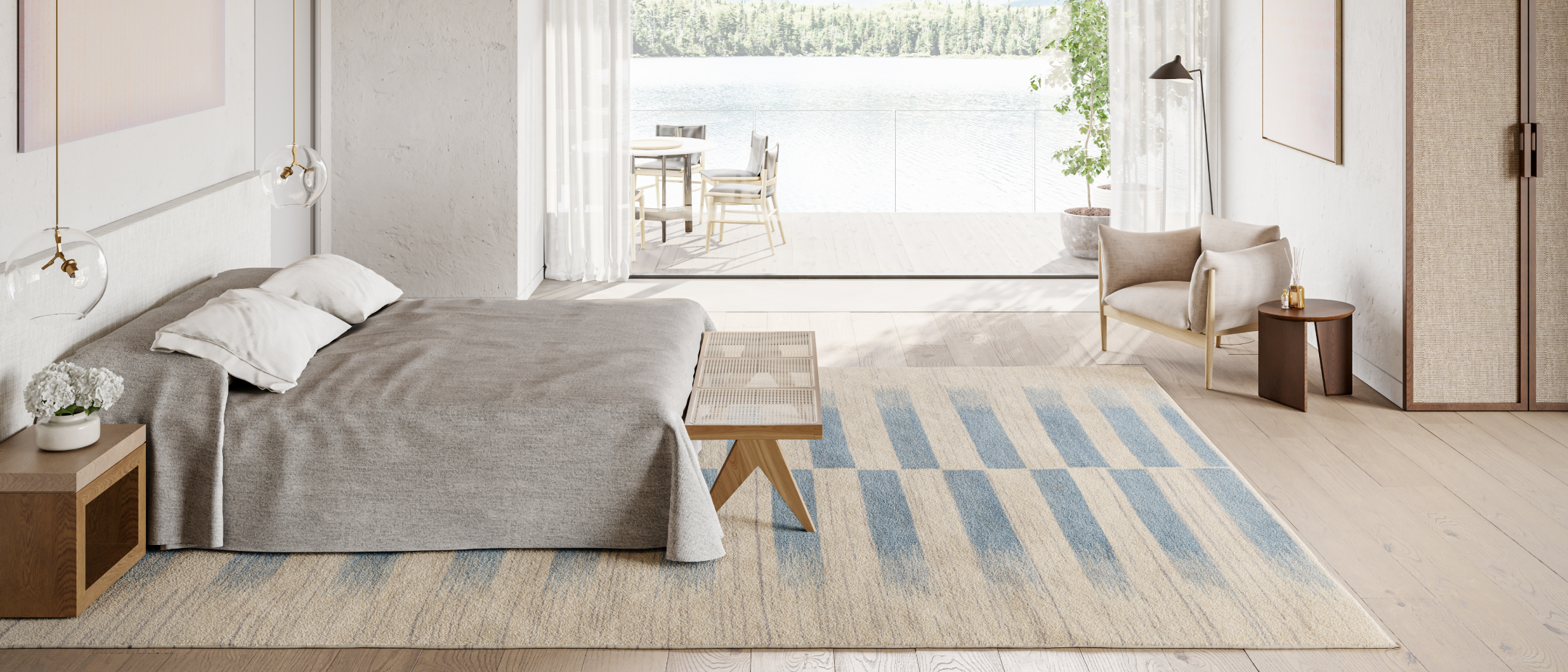 Modern bedroom with rug, bed, bench, and side table leading outside to a lake view.